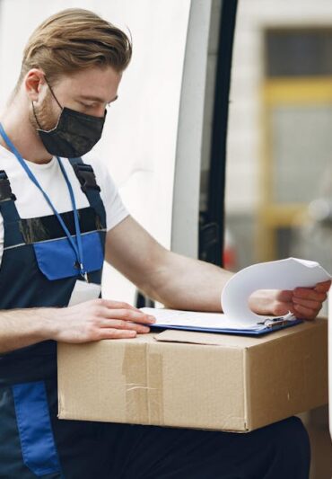 Courier delivery worker reviewing package documents before shipment